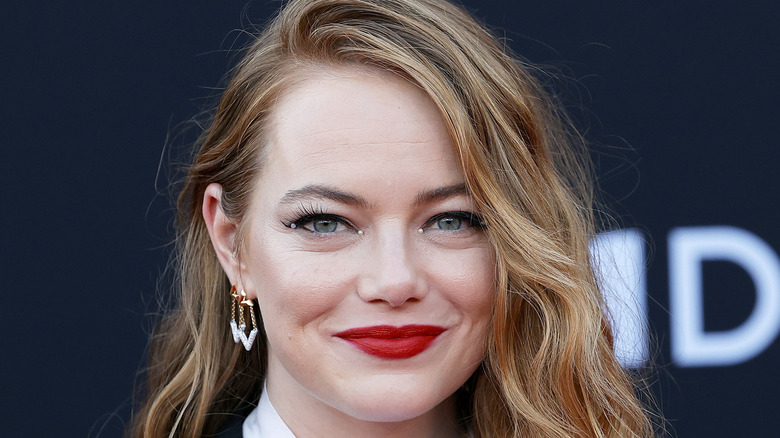 Emma Stone smiles while wearing red lipstick