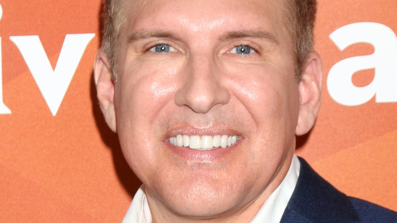 Todd Chrisley smiles against orange backdrop