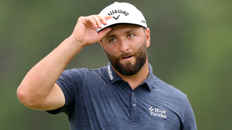 Jon Rahm fixing hat on golf course